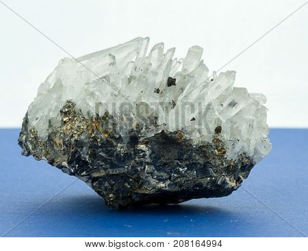 Crystals growing out oi f small stone blue surface white backgounrd