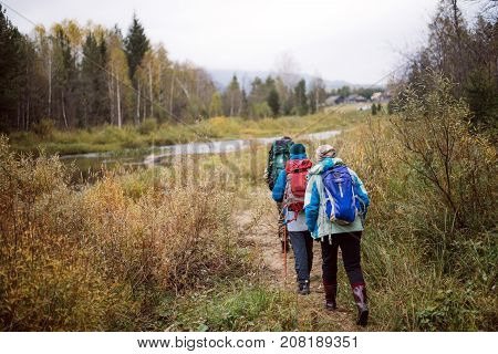 Tourists walking along the river Bank in autumn day