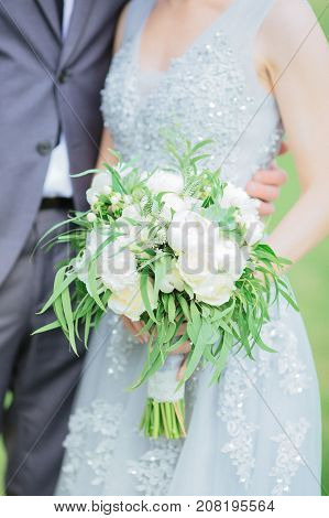 Wedding bouquet in hands of the bride near her broom