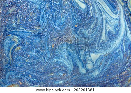 Marbled blue abstract background with golden sequins. Liquid marble ink pattern