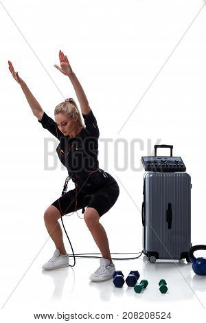 Beautiful EMS fitness woman doing training squats. Isolated on white background.