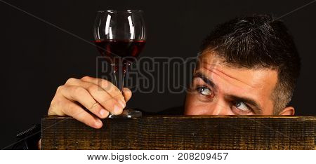 Man With Beard Holds Glass Of Wine On Brown Background