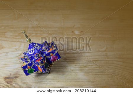 Blue enameled decorative star shaped Hanukkah dreidel on a wood table