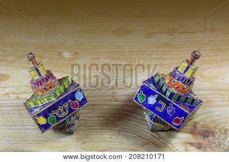 Two multicolored Hanukkah dreidels on a wood tabletop with space for text