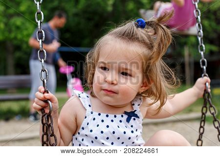 Cute happy little girl at playgraund swing