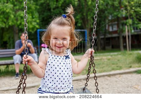 Cute smiling little girl at playgraund swing