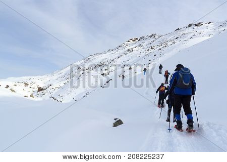 Group of people hiking on snowshoes and mountain snow panorama with blue sky in Stubai Alps Austria