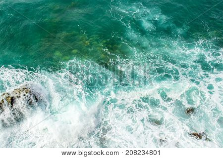 Sea waves break up on the stones of the coast. The raging sea and foam. View from above. Green background.