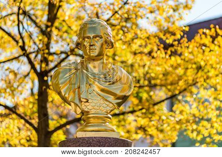 A golden statue with autumn trees in the background on the Old Town Square in Bischofswerda, Germany.