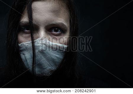 wounded woman with wounded face on black background with copy space looking at camera