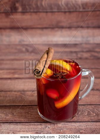 Glass Cup of red wine mulled wine on a wooden background with cinnamon spices and orange. Selective focus.