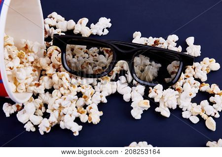 Spilled popcorn and 3d glasses on a blue background. Close-up. View from above.