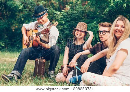 Happy teenagers singing together with guitar .