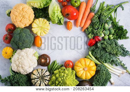 Various colorful vegetables arranged in a circle on the light grey background, copy space for text in the middle, selective focus