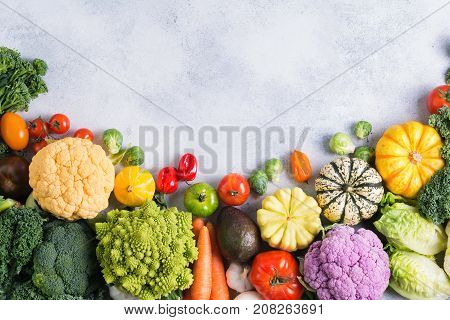 Above view of different colored rainbow vegetables on the light grey background, copy space for text above, selective focus