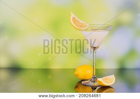 Glasses of cream liqueur with lime and lemon on green background with reflection. Short of lemon liqueur. Traditional Italian alcoholic beverage Limoncello