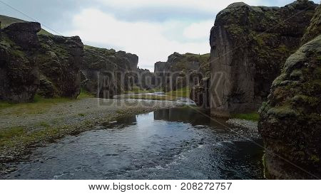 flying through the drone through the canyon Fjarrgljfur and the river going inside it on a sunny day in southern Iceland