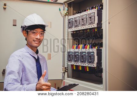Control Room Engineer. Power Plant Control Panel. Engineer standing in front of the control panel in the control room and write the results of the measurements.