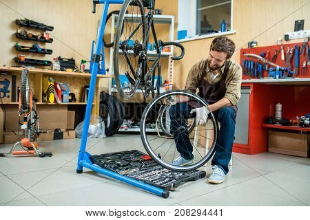 Repair specialist holding bicycle wheel over toolkit while checking it up