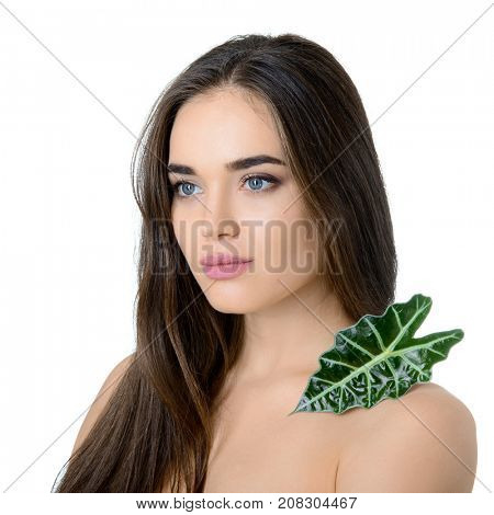 Gorgeous girl with cleann skin and perfect hair holding green fresh leaf on her shoulder, isolated on white. Beautiful young woman's portrait. Care of mother-nature. Natural cosmetics concept.