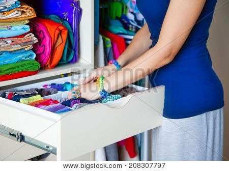 Neatly Folded Clothes With Accessories In Chest Of Drawers