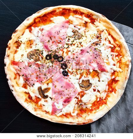 Delicious raw italian pizza on black concrete background with Copyspace. Pizza with han bacon cheese and fresh ingredients