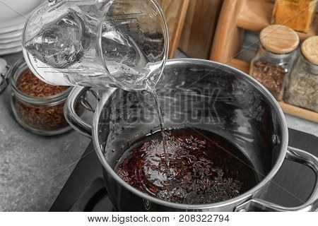 Pouring water into stewpot with boiling rice