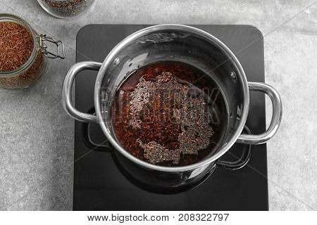Stewpot with raw rice and water in kitchen