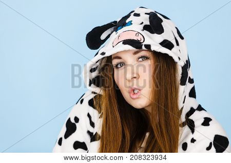 Happy teenage girl in funny nightclothes pajamas cartoon style making silly face positive face expression studio shot on blue.