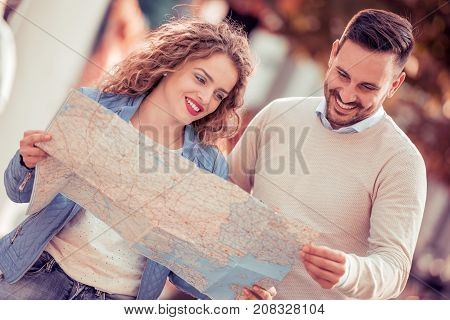 Loving couple with a map looking for an address on the strreet.