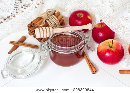 Red apples with cinnamon and honey on white wooden table. Autumn or winter background