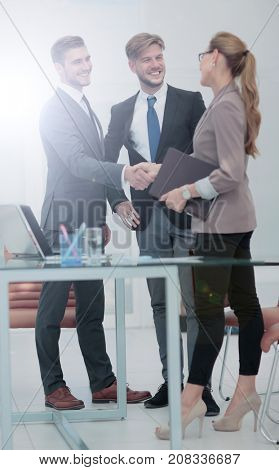 Happy smiling business people shaking hands after a deal in offi