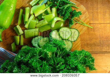 Sliced peppers cucumbers with parsley and argula on rustic wooden table