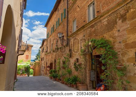 Pienza, Italy - May 27, 2017: Beautiful narrow street with sunlight and flowers in the small magical and old village of Pienza, Val D'Orcia Tuscany.