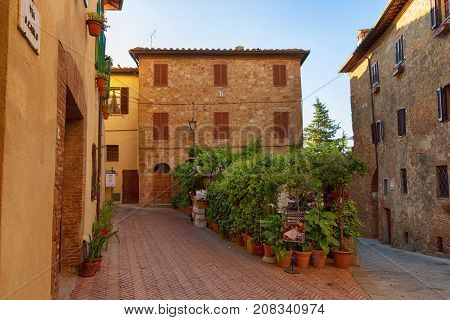 Pienza, Italy - May 27, 2017: Beautiful narrow street with sunlight and flowers in the small magical and old village of Pienza, Val D'Orcia Tuscany.