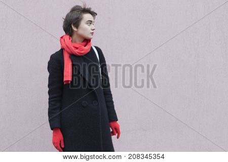Dramatic Portrait Of Young Melancholy Woman In A Red Scarf And Gloves Against Cocrete Wall. Concept