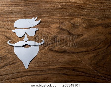 Hipster's definicial facial look cut from paper on the wooden background.