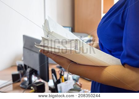 Female office workers holding are arranging documents of unfinished documents on office desk Stack of business paper.