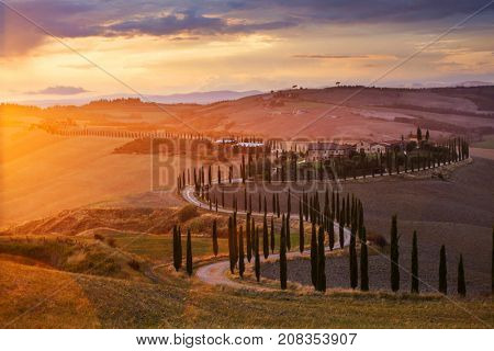 Tuscany, Italy - September 27, 2017: Lonely farmhouse with cypress trees and rolling hills in autumn sunset near Crete Senesi, Tuscany, Italy. 