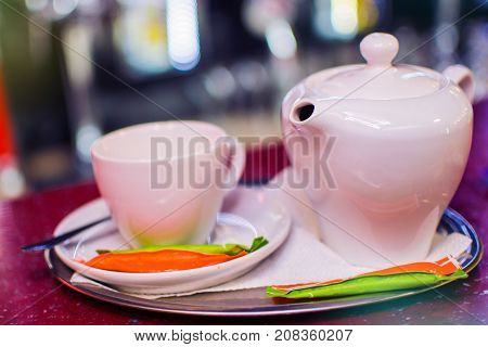 white ceramic kettle and a white mug on a saucer.