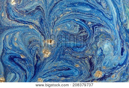 Marbled blue abstract background with golden sequins. Liquid marble ink pattern