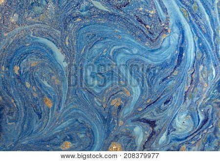 Marbled blue abstract background with golden sequins. Liquid marble ink pattern