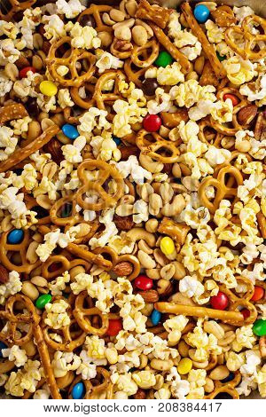 Homemade trail mix for kids with chocolate candy, popcorn, pretzels and nuts overhead shot
