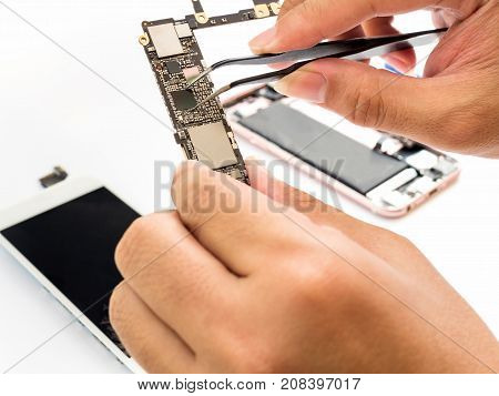 Close-up of technician hand clamping processor on smartphone logic board on blurred smartphone component background