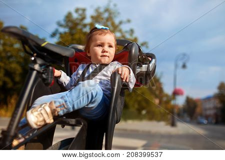 Little girl in the seat bicycle. Happy kid smiling on bicycle