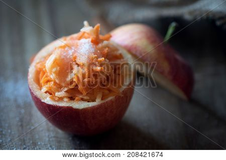 A healthy salad of carrots and apples sprinkled with sugar in an apple. Healthy dessert