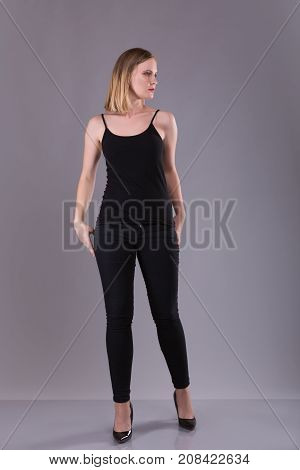Blonde woman in bkack suit on gray background in studio photo.