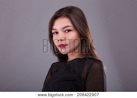 Beautiful brunette model: classic makeup and red lips. The beauty face. Studio shoot over gray background