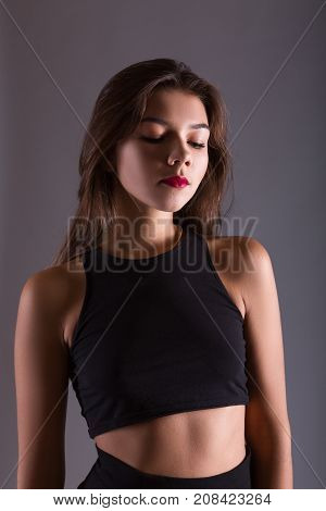 Closeup fashion portrait of sensuous woman looking down on gray background. Studio shoot
