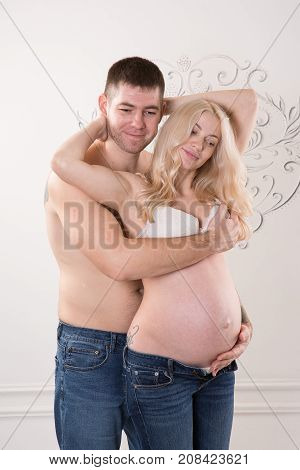 Beautiful pregnant couple in love on the background. Hands of husband on the tummy of his pregnant wife. Young man tenderly stroked pregnant belly of his wife. Husband kissing pregnant belly.